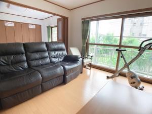 广岛Itsukaichi First Villa Hiroshima的客厅配有真皮沙发和跑步机
