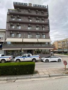 亚历山德鲁波利斯埃里卡酒店的一座大型建筑,前面有汽车停放