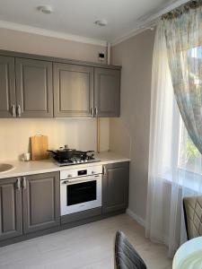 库斯塔奈2-ухкомнатная современная новая квартира в центре города的厨房配有灰色橱柜、炉灶和窗户。