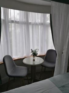 佩恩顿蓝色水域旅舍的窗户前设有2把椅子和1张桌子的房间