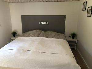 斯卡恩Hyggelig ferielejlighed的卧室配有一张带两张桌子的大型白色床