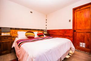 圣佩德罗·德·阿塔卡马Hotel Casa Algarrobo的卧室配有白色的木墙床