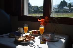 PumarínHotel Las Catedrales的一张桌子,上面有早餐食品和两杯橙汁