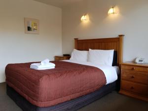 基督城紫檀阁汽车旅馆 的一间卧室配有一张带红色毯子的大床