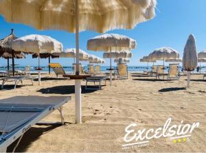 蒙特西尔瓦诺Hotel Excelsior的沙滩上带椅子和遮阳伞的海滩