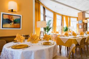 兰佐丁泰尔维米兰SNC酒店的餐厅设有白色的桌椅和黄色的墙壁