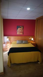 阿维拉多纳胡安娜旅舍的一间卧室配有一张黄色的床和红色的墙壁