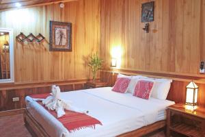 琅勃拉邦苹果旅馆的卧室配有一张白色大床和木墙