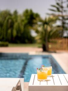 皮吉Tsourlakis Residence, an oasis of tranquility, By ThinkVilla的池畔餐桌上的两杯饮料
