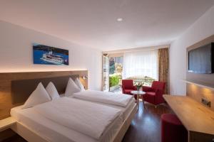 因特拉肯瑞士小屋酒店的酒店客房带白色的床和红色椅子