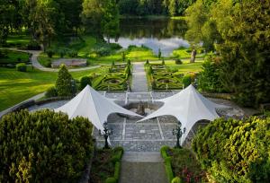 科沙林Hotel Bursztynowy Pałac的花园内有两把白色遮阳伞,花园内有池塘
