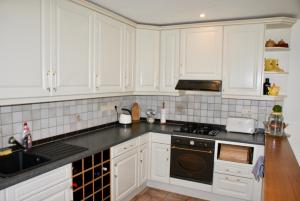 斯塔沃洛Sofiya Apartment的厨房配有白色橱柜和黑炉灶烤箱。
