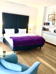 科布伦茨Stein Boardinghouse的一间卧室配有一张带紫色毯子和椅子的床