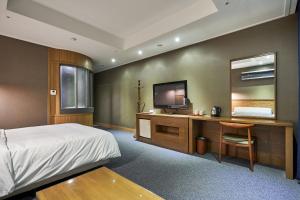 富川市高丽酒店的一间卧室配有一张床和一张书桌及电视