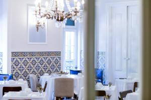 里斯本圣保罗曼德酒店的一间设有白色桌子和吊灯的用餐室