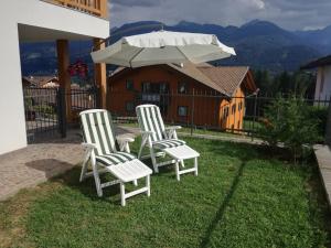 卡瓦莱塞Villa in Val di Fiemme的院子里有两把白色椅子和一把遮阳伞