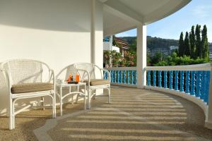 苏林海滩Pen Villa Hotel, Surin Beach - SHA Extra Plus的阳台的门廊配有2把椅子和1张桌子