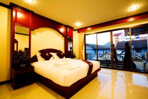 芭东海滩Baan Sudarat Hotel的一间带大床的卧室和一个阳台