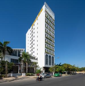 岘港Gold Plaza Hotel Da Nang的上面有黄色标志的高大的白色建筑