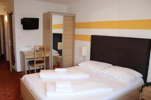 维也纳雷纳斯都瑙酒店的一间卧室配有一张带白色床单的床和一张书桌。