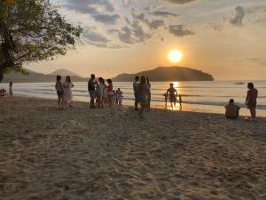 乌巴图巴绿色港湾旅舍的一群人,在日落时站在海滩上