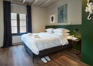 登博斯The Guest Apartments - Uilenburg的卧室配有一张带白色床单和枕头的大床。