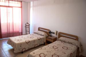 Mora la NuevaHostal Fontdemora的一间卧室设有两张床和窗户。