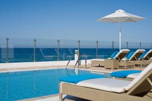 普罗塔拉斯Althea Kalamies Luxury Villas的一个带椅子和遮阳伞的游泳池以及大海