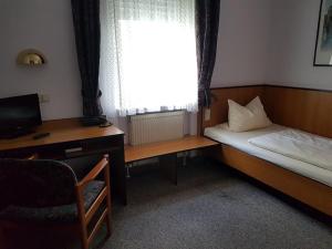 费尔巴赫Traube Hotel Oeffingen的一间卧室配有一张床、一张书桌和一个窗户。