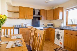 因弗内斯Modern 2 bedroom garden flat的厨房配有木制橱柜和1张带洗衣机的桌子。