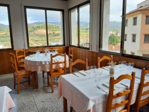 Pinell de BrayCa l'Àngel的餐厅设有白色的桌椅和窗户。