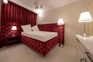 布加勒斯特Hotel Casa Fiori的红色卧室配有一张带两盏灯的床