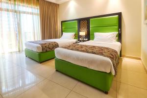阿吉曼巴希阿治曼宫酒店 的配有绿色床头板的酒店客房内的两张床