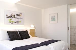 阿尔森斯Margueda的白色卧室配有白色的床和黑色枕头