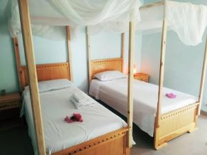 KafountineCan Teranga的卧室内的两张床,上面有鲜花