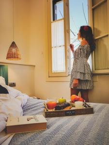 休达德亚Hotel Romantic Los 5 Sentidos的站在床上看着窗外的年轻女孩