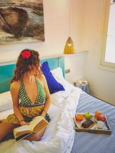 休达德亚Hotel Romantic Los 5 Sentidos的坐在床上读书的女人