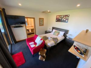 普纳凯基Tasman Sea Retreat的酒店客房,配有一张床和一张红色椅子