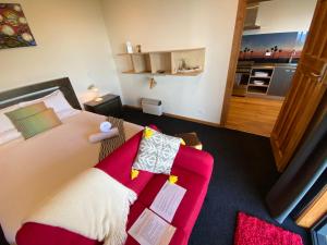 普纳凯基Tasman Sea Retreat的一间卧室配有一张床和一张红色的沙发