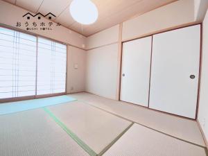 广岛OUCHI HOTEL Itsukaichi的一间空房间,拥有白色的墙壁和窗户