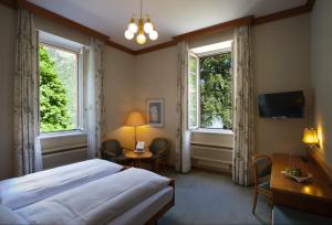 波斯基亚沃波斯基亚沃普莱斯酒店的一间卧室配有一张床、一张书桌和两个窗户。