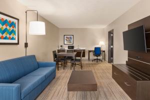 迈尔斯堡Holiday Inn Express Hotel & Suites Fort Myers East - The Forum, an IHG Hotel的客厅配有蓝色的沙发和桌子