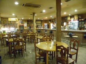 阿雷瓦洛Hostal Las Fuentes的一间带木桌椅的餐厅和一间酒吧