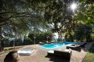 科尔恰诺Villa Piscina “La Trinità “的一个带躺椅的游泳池以及一棵树