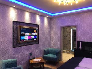 科隆City Luxus Appartement nähe Köln Messe - LANXESS Arena的一间卧室设有紫色的墙壁,墙上配有电视。