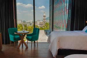 蒙特雷Hotel Kavia Monterrey的酒店客房带一张床、一张桌子和椅子