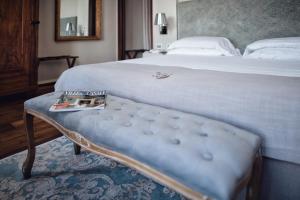 阿利亚诺泰尔梅Villa Fontana Relais Suite & Spa的一间卧室配有一张床和一张带杂志的长凳