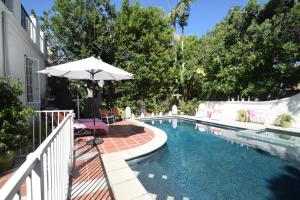 洛杉矶贝弗利山名人之家别墅的一座房子旁的游泳池,配有遮阳伞和椅子