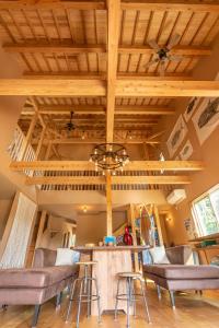石垣岛YOISAMA Sunset Beach House的一间带木制天花板的客厅和一间带凳子的酒吧