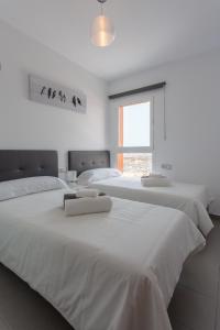 罗萨里奥港Mariposas Home Pool的白色卧室设有2张白色床和窗户。